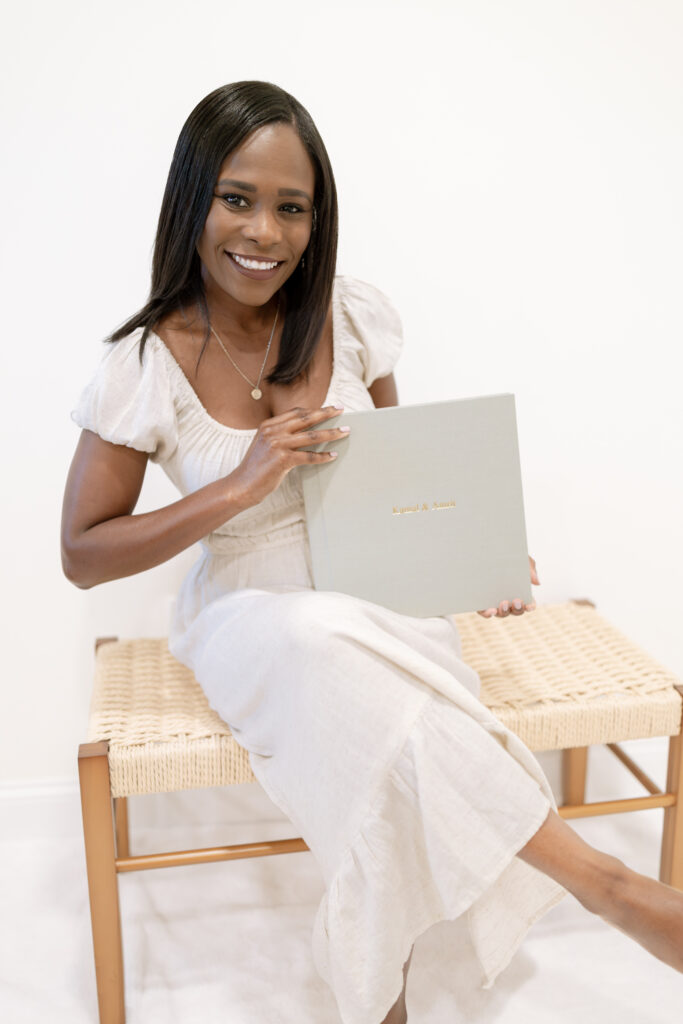 A woman sits on a bench holding a green linen photo album.